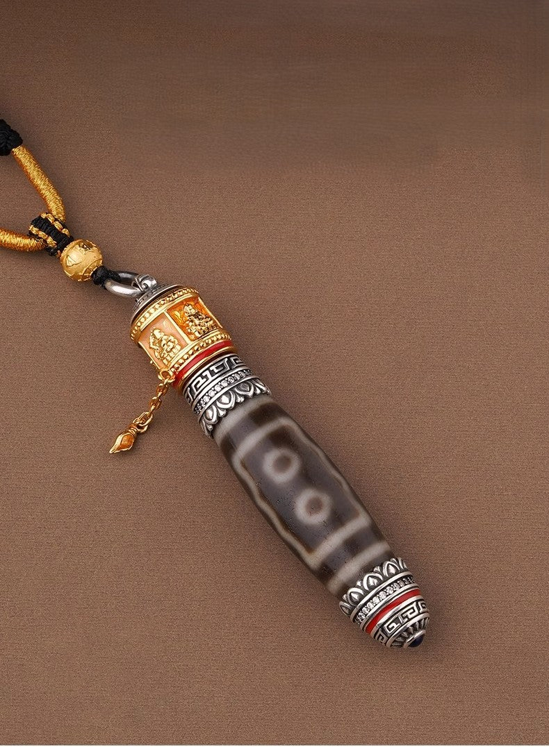 Tibetan dzi pendant with gold trim laid on brown 