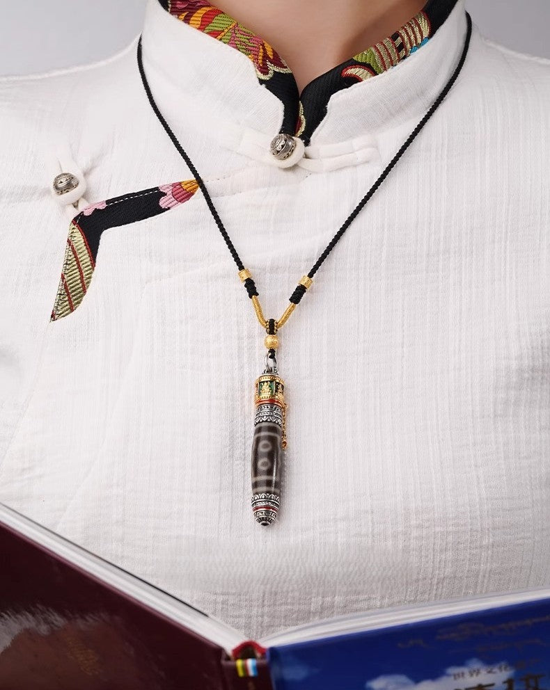 Model wearing Tibetan dzi prayer wheel necklace in traditional white top
