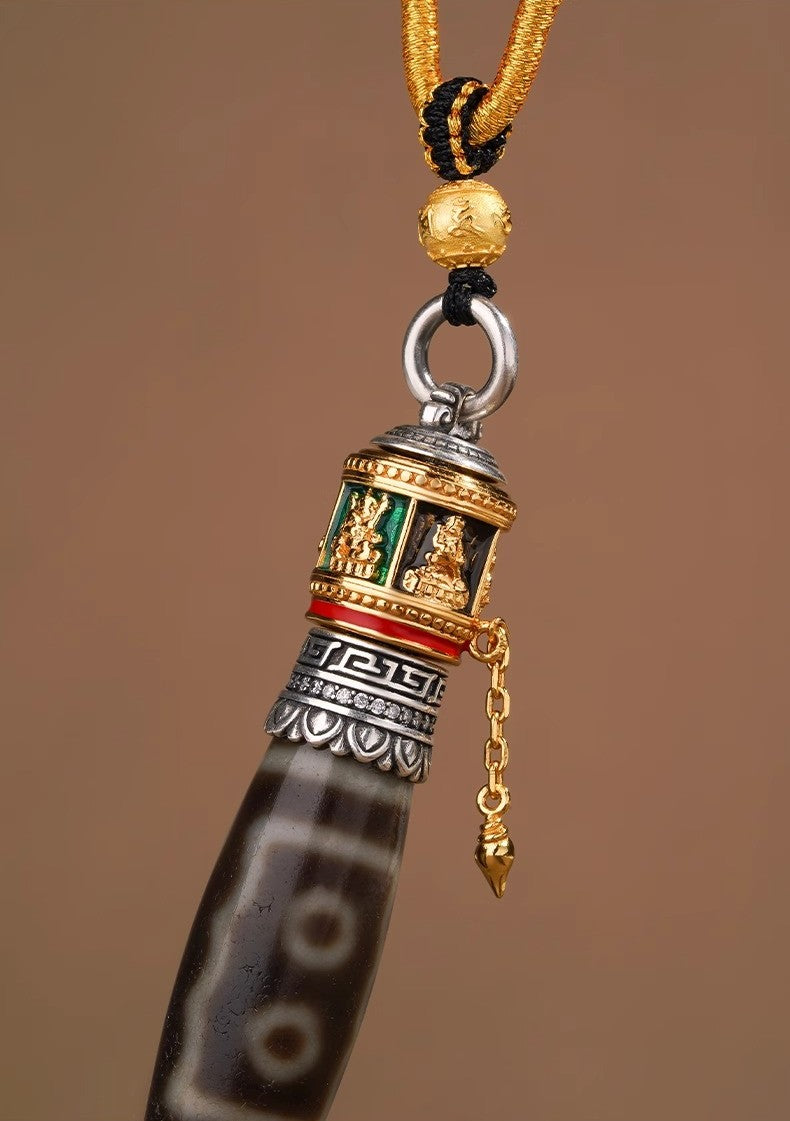 Close-up of rotating prayer cylinder on dzi necklace with gold chain