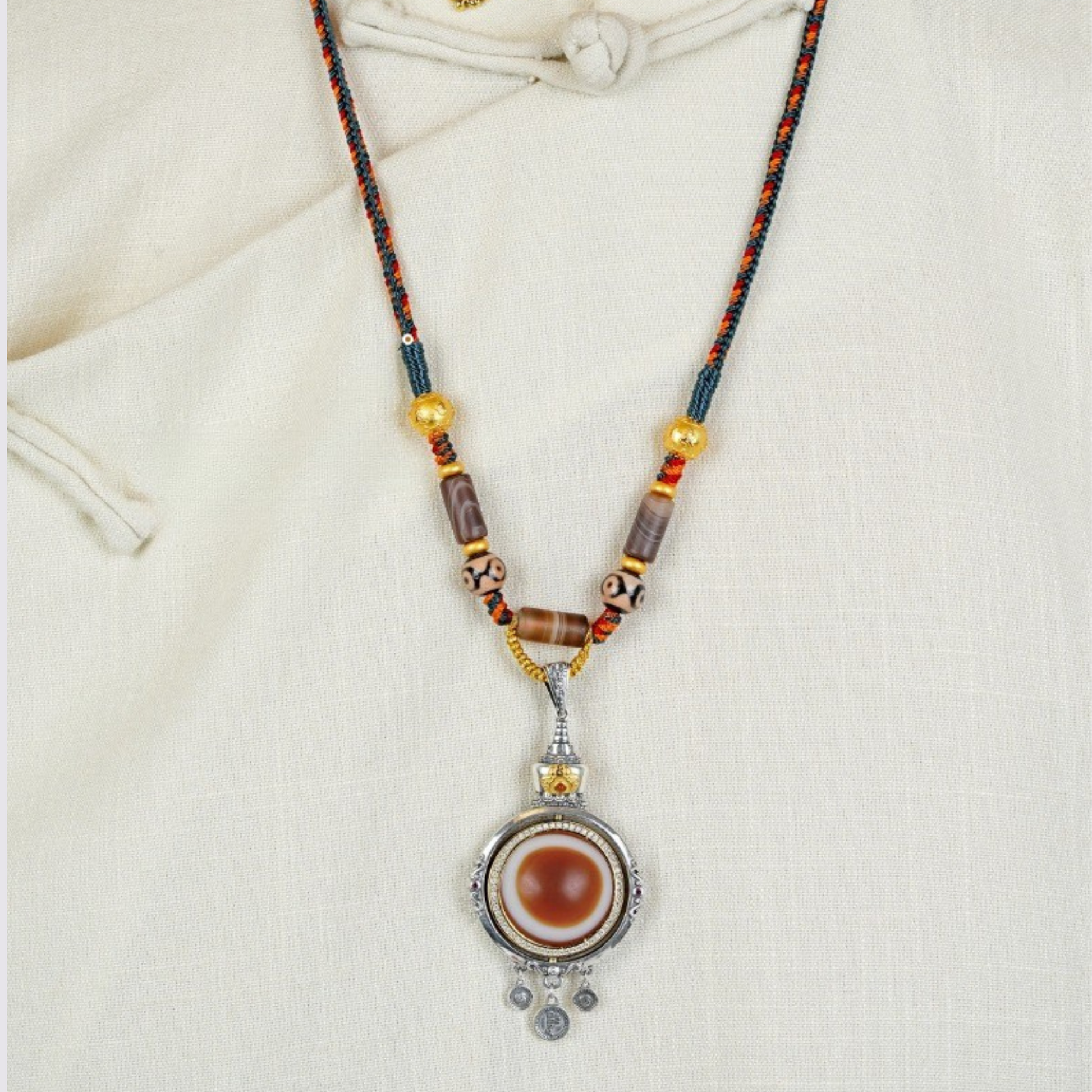 Model wearing handmade Tibetan dzi pendant necklace with red-blue cord on white clothing